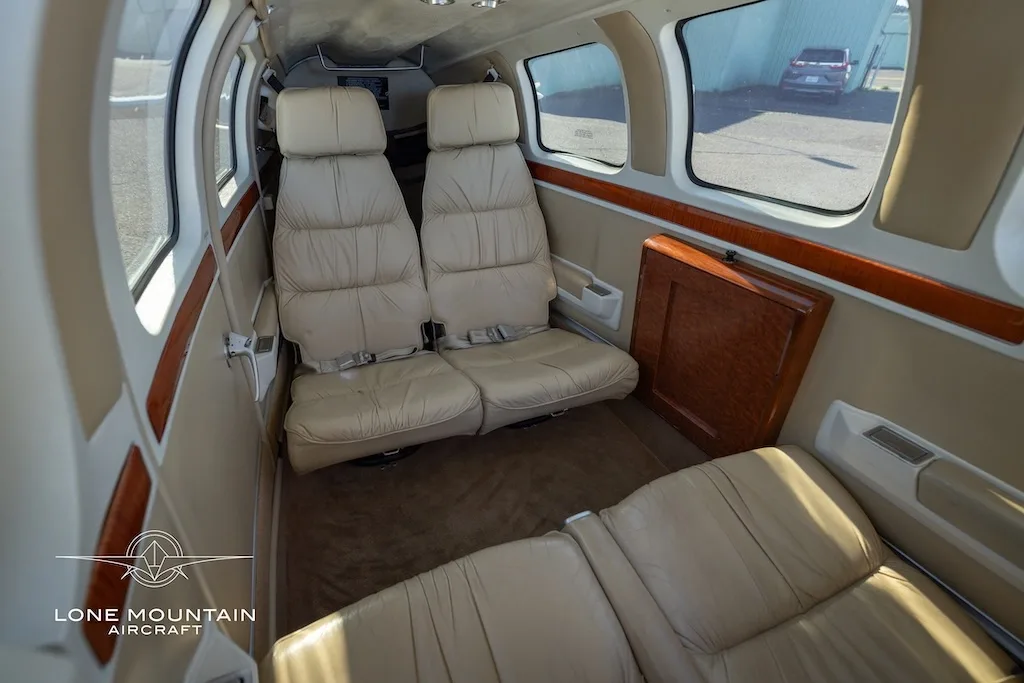 The beige leather interior cabin of the aircraft, showing two rear seats and a side table.