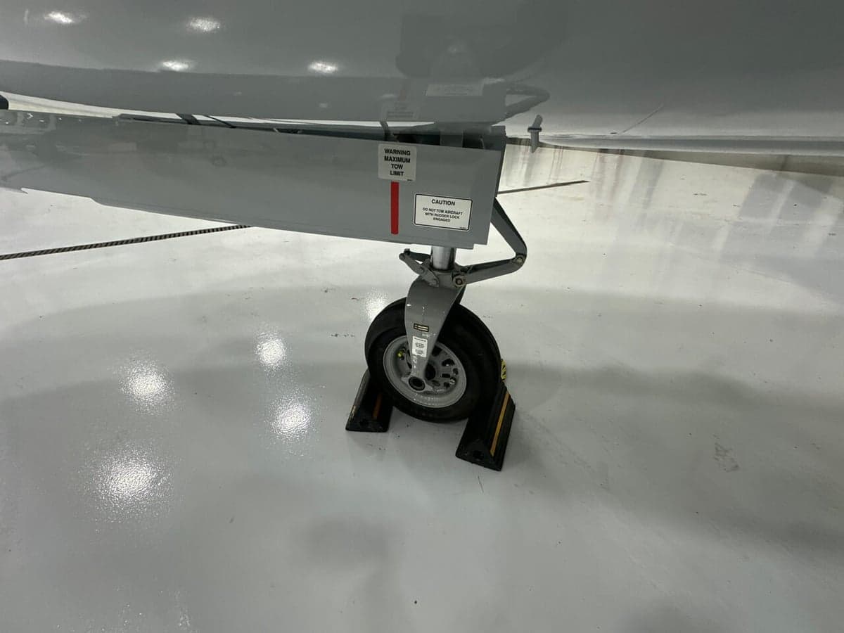 Close up of the aircraft's nose wheel and strut in a hangar setting.