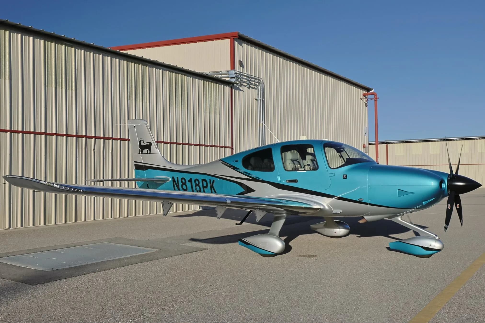A three-quarter front view of a teal and silver Cirrus SR22T GTS aircraft (N818PK) parked on an airfield.