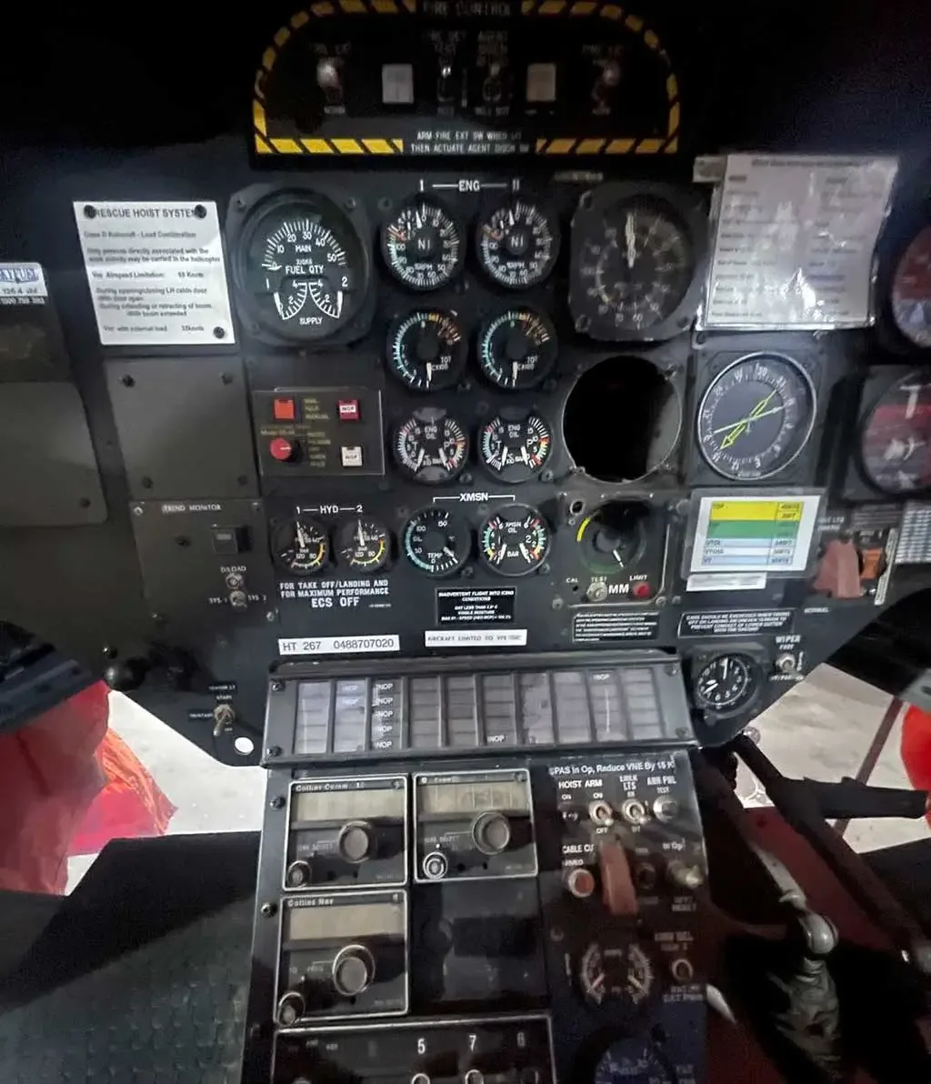 A detailed close-up of a helicopter's instrument panel, highlighting the gauges and lower control console.