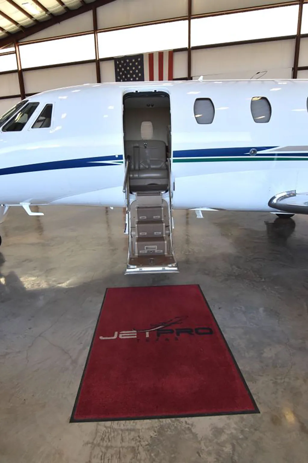 A close-up view of the open main cabin door and integrated airstairs of a white Cessna Citation XLS jet, with a "JETPRO TEXAS" mat on the floor.