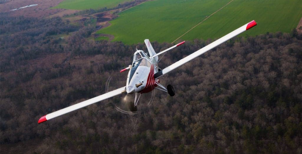 Front view of a Thrush 510G crop duster flying over a forest.