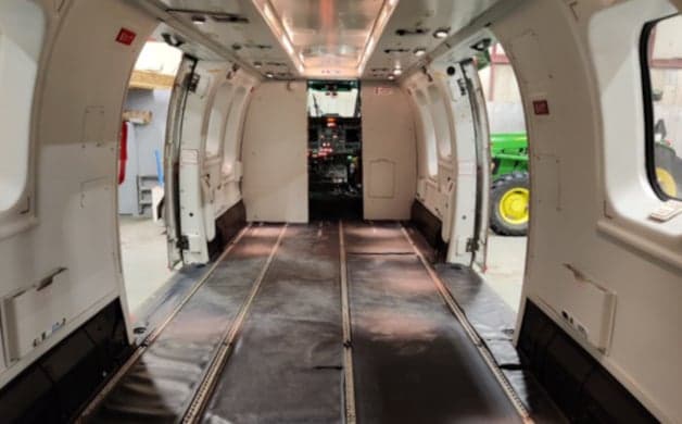 White helicopter with open doors in a hangar.