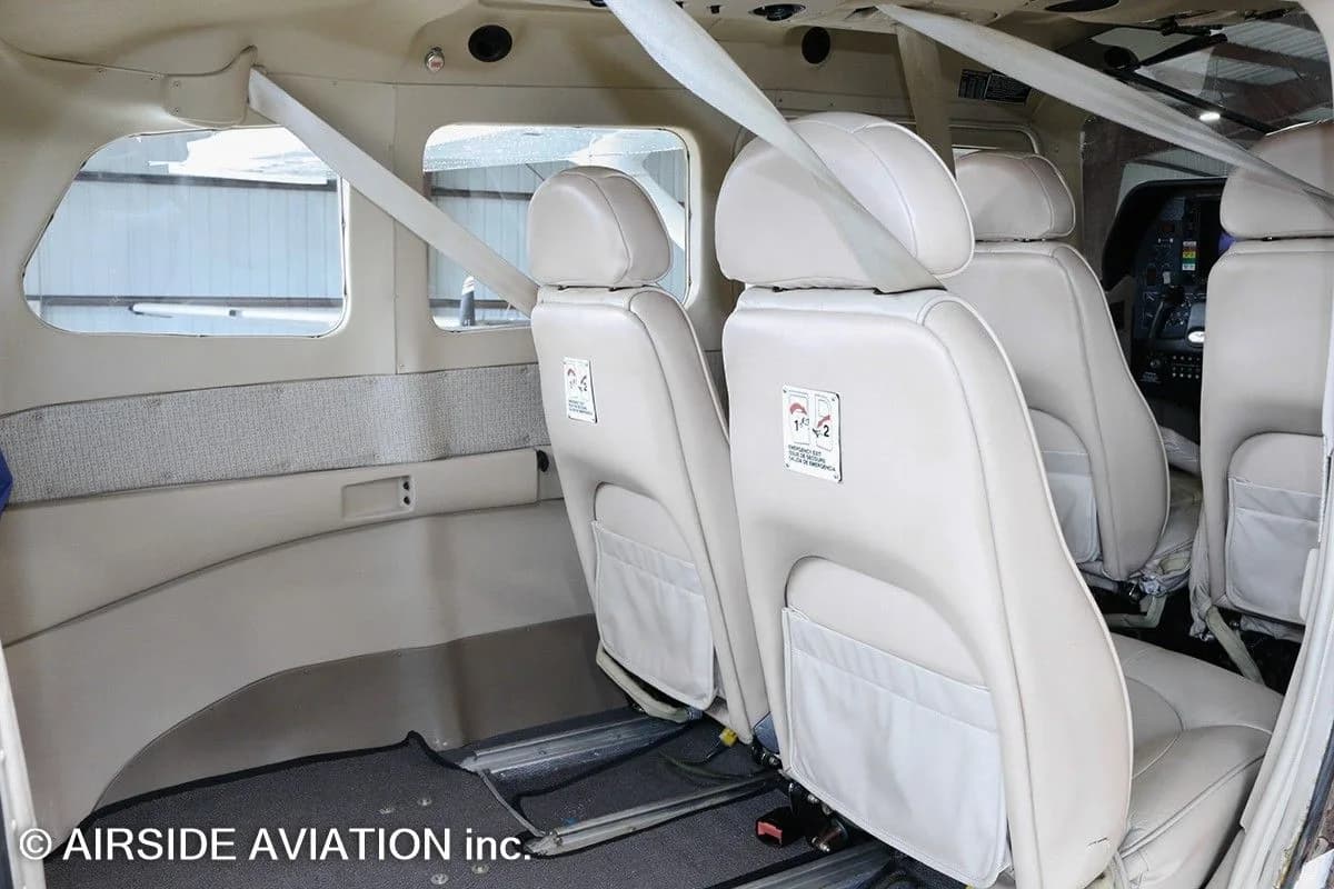 The aircraft's interior cabin features beige seats with seatbelts and light-colored paneling.