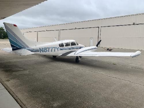 A Piper Aerostar aircraft with blue stripes is parked on the tarmac.