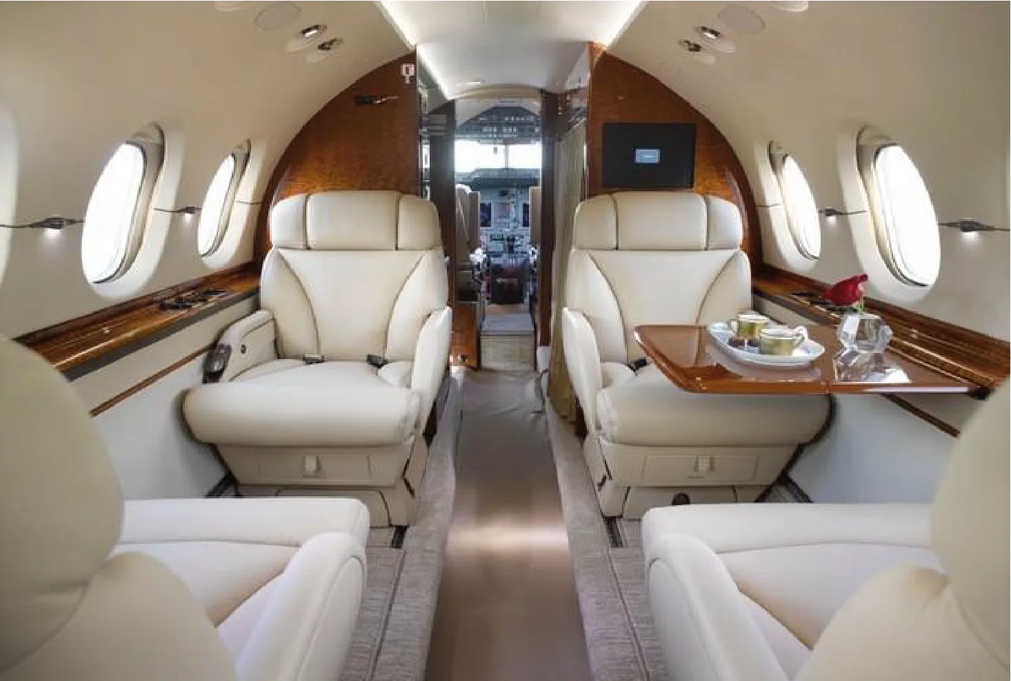 Aircraft interior with cream-colored leather seats and wood trim, looking towards the cockpit.