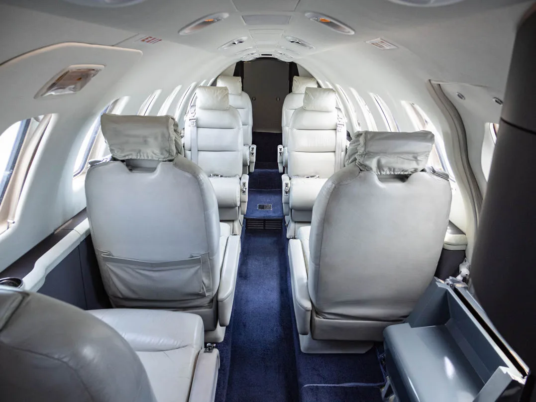 View down the aisle of the aircraft cabin with white leather seats.