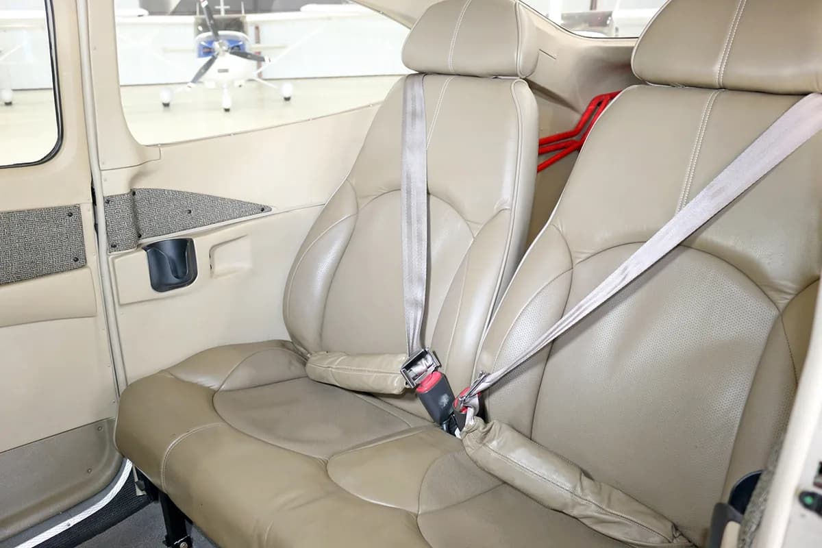 Tan leather passenger seats with seatbelts in the aircraft cabin.