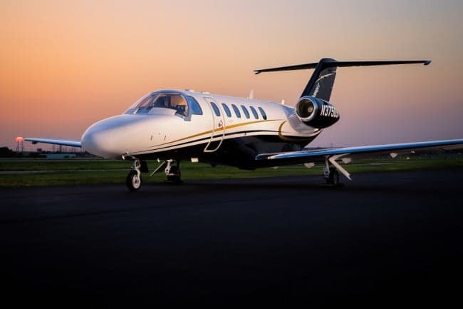 A Cessna Citation CJ3+ aircraft with registration N375DS is parked on the tarmac at sunset.