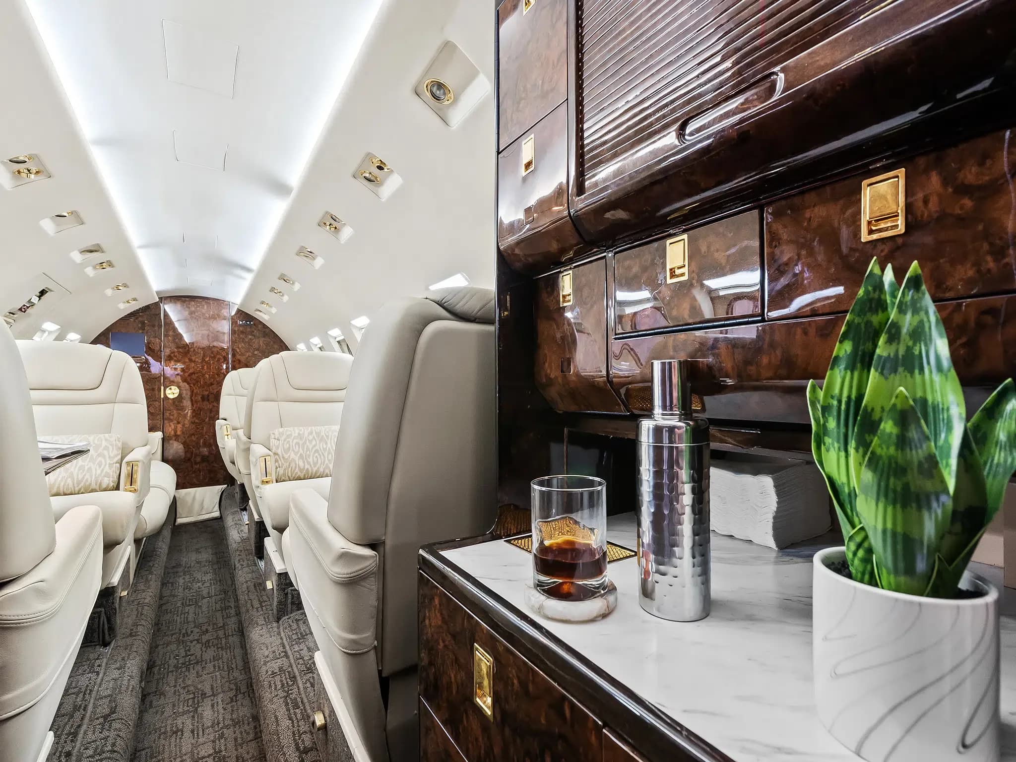 View of the aircraft cabin with a bar area and leather seats.