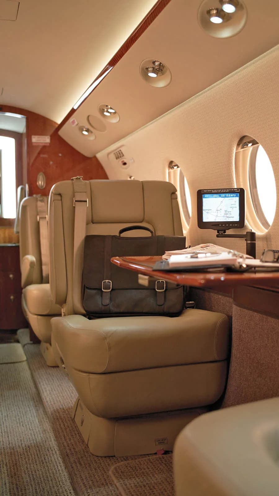 Aircraft cabin seats with a briefcase and table.