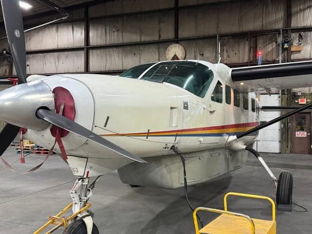 Close-up of a turboprop aircraft in a hangar, showing the nose and propeller.