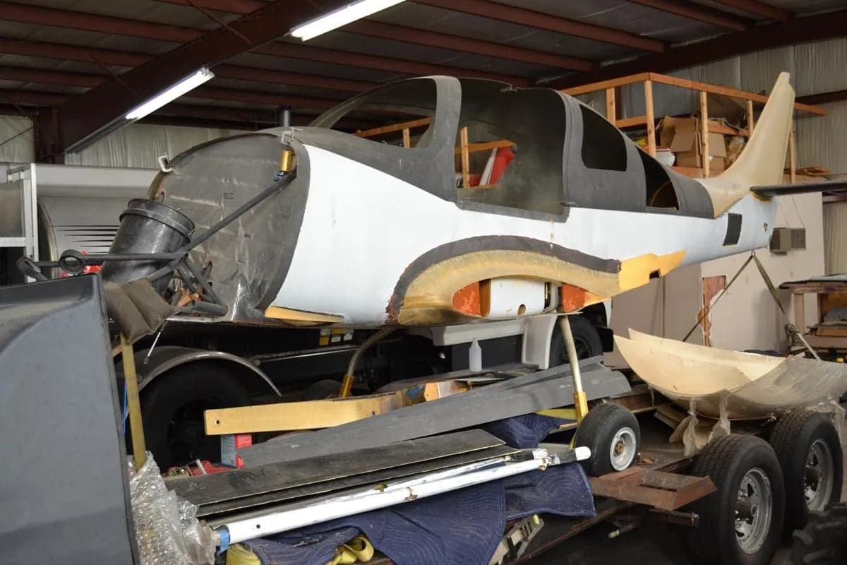 An aircraft fuselage and tail section on a trailer in a hangar.