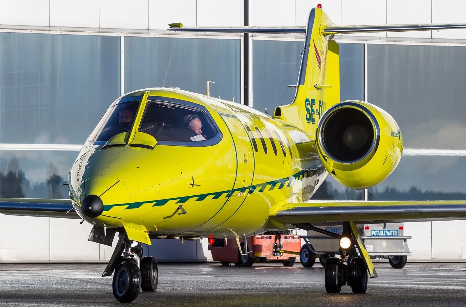 Front view of a yellow ambulance jet on the tarmac.
