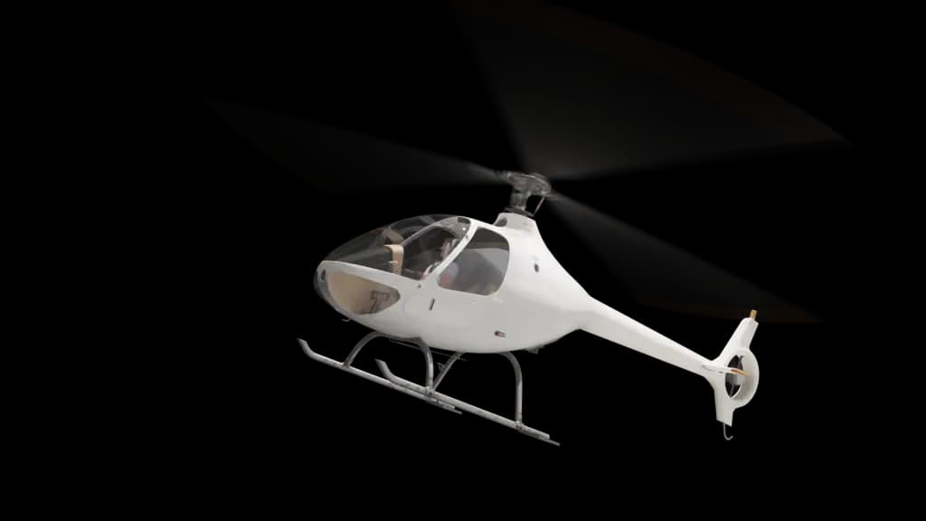 A white helicopter with orange-tipped rotor blades is shown from a low angle, appearing to be in flight against a plain background.