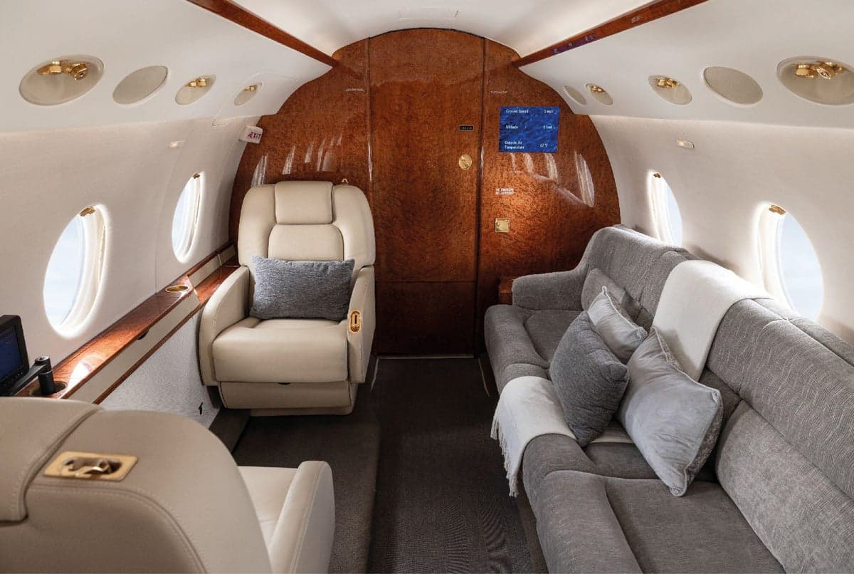 Aircraft cabin featuring a sofa and leather seat.