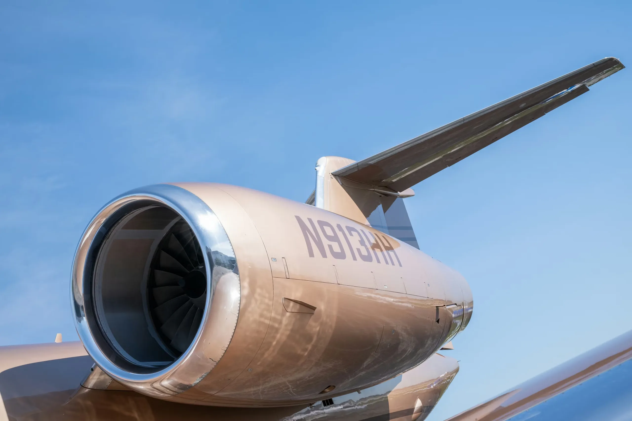 Close up of the tail and engine of a bronze Gulfstream jet.
