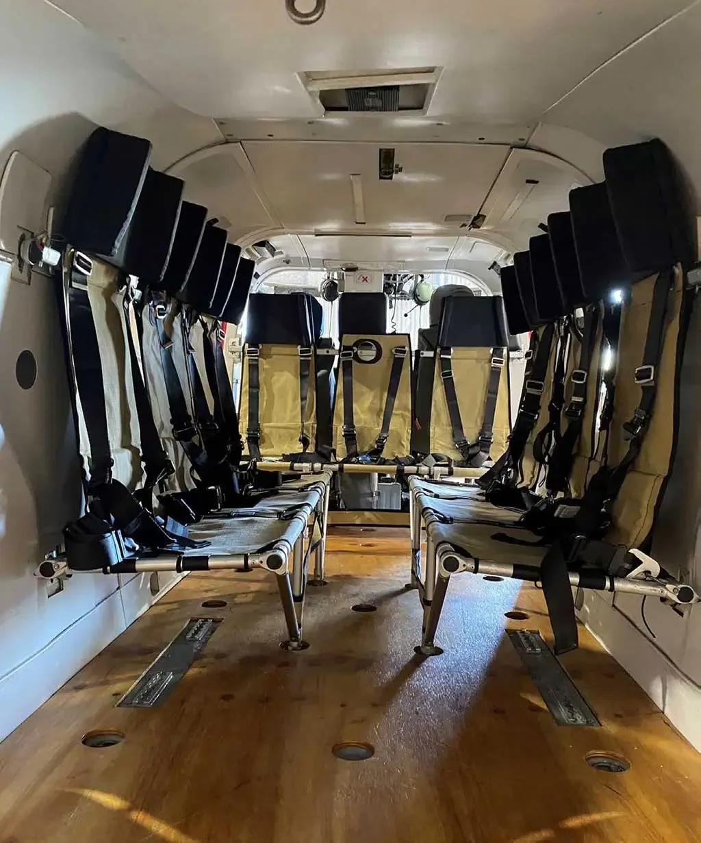 A wide view of the helicopter's interior cabin, showing two rows of tan fabric seats with black harnesses.