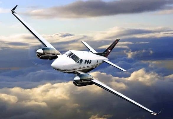 Stock photo of a Beechcraft King Air in flight against a cloudy sky.