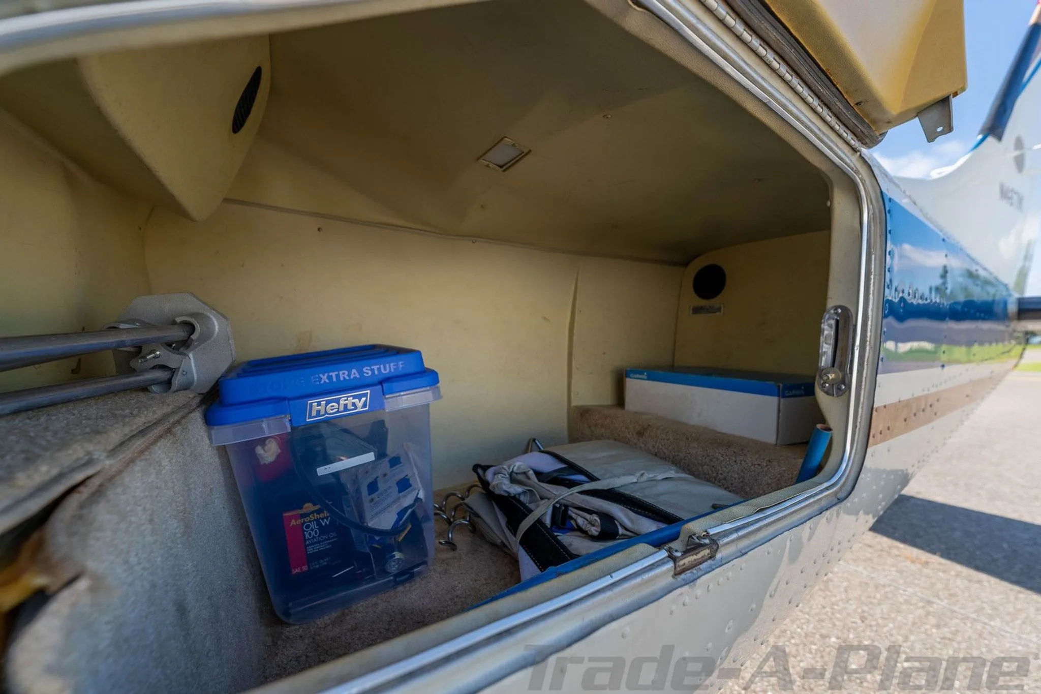 The open cargo compartment of the aircraft, revealing a blue storage bin and other items.
