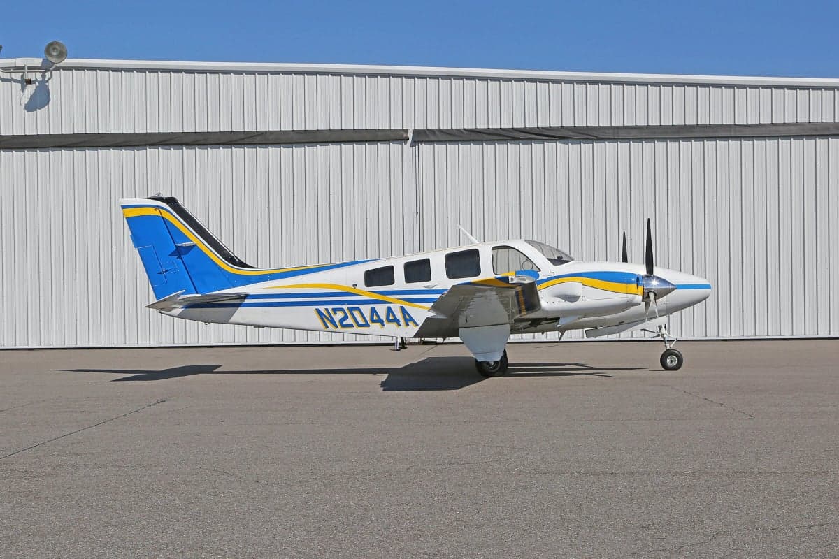 Side view of a Piper PA-31 Navajo Chieftain aircraft with registration N2044A parked on the tarmac in front of a hangar.