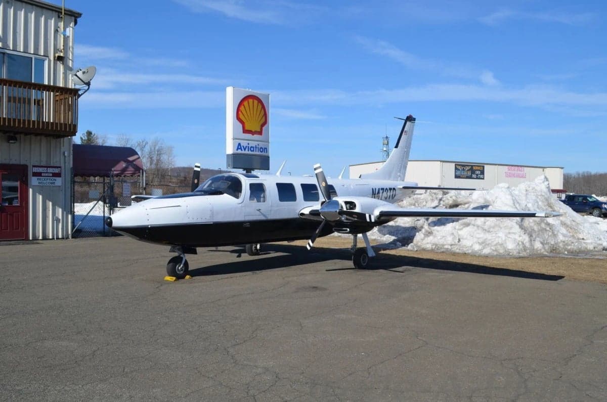 The aircraft's interior features gray leather seats and wood trim.