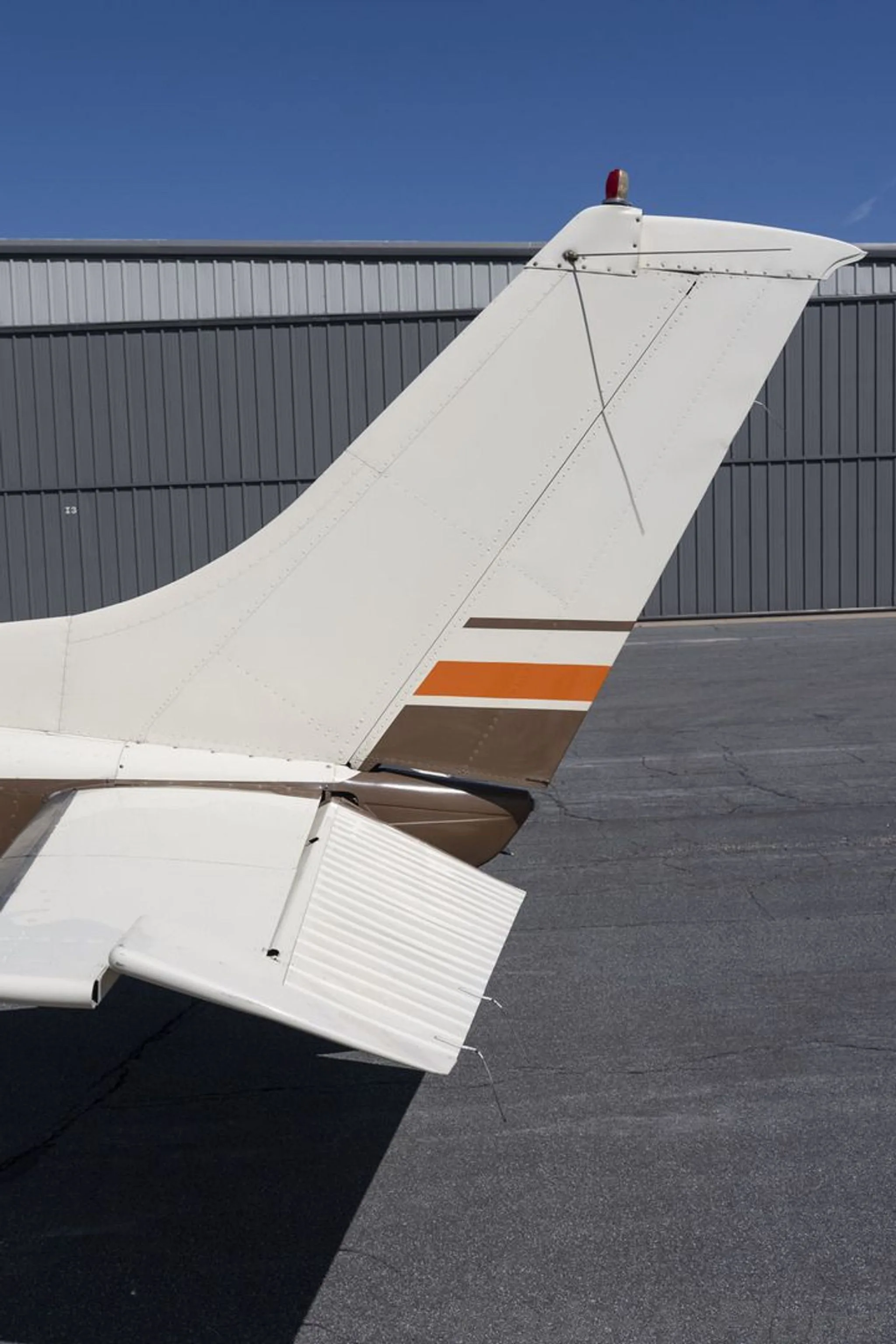 A close-up view of the white tail and horizontal stabilizer of the aircraft, with brown and orange stripes.