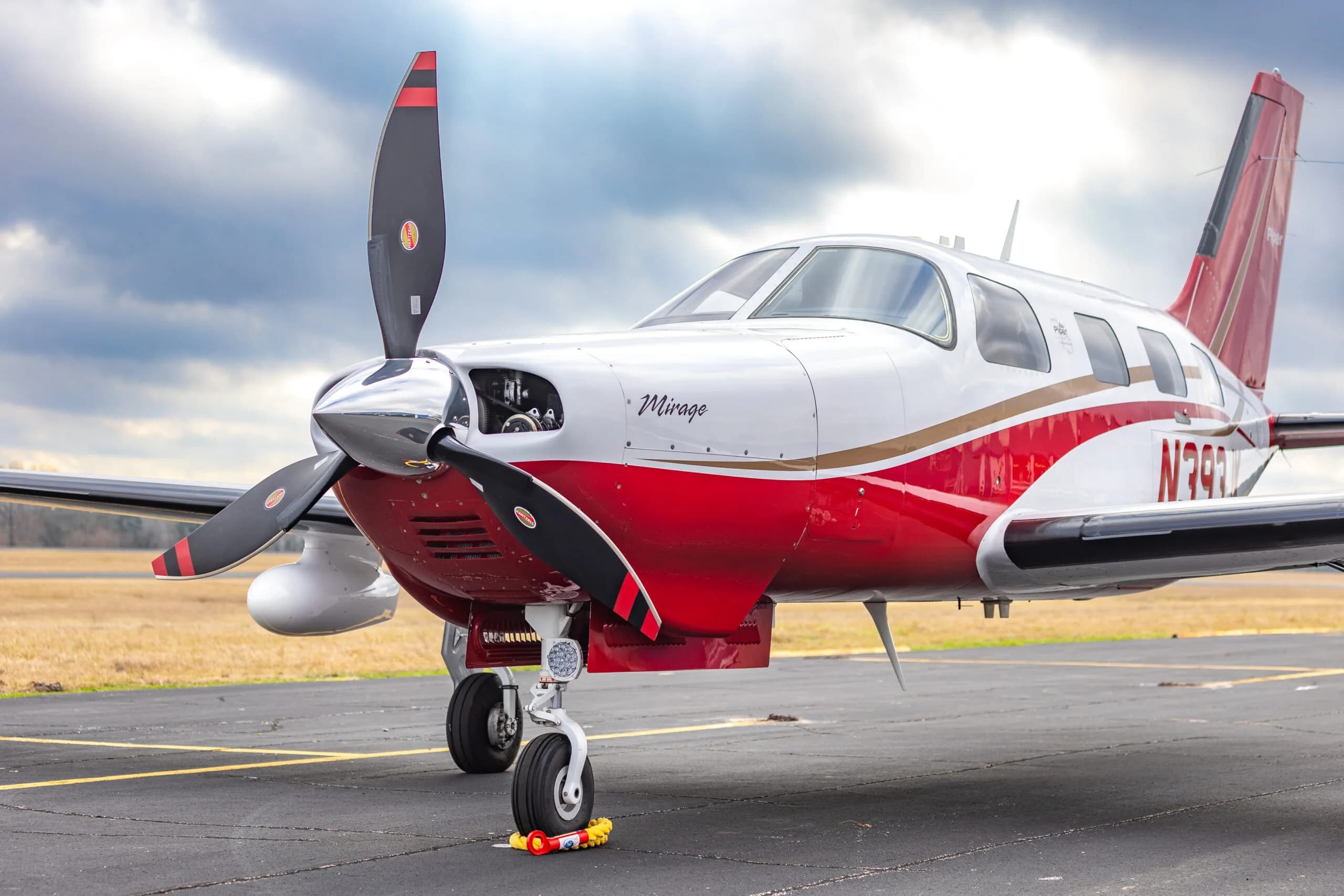 Close-up of the front of the Piper Mirage N393JK, focusing on the propeller and nose.