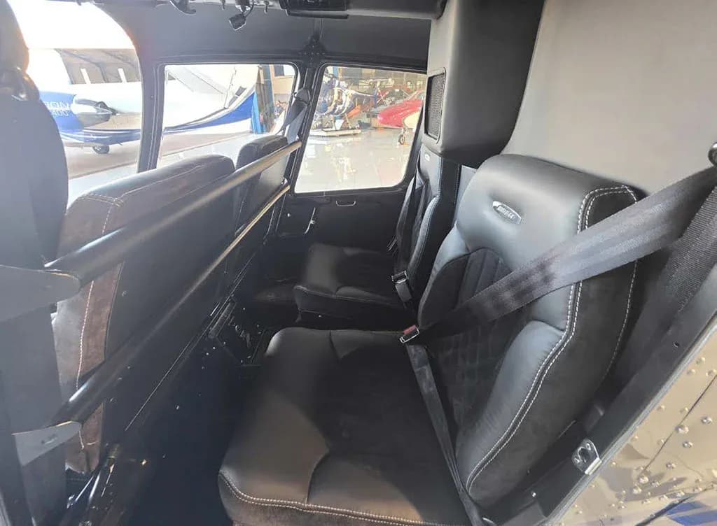 The black leather and suede interior seats of a helicopter cabin, looking towards the front.