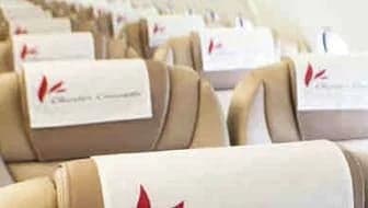 Close-up of aircraft seats with headrest covers featuring a red logo.