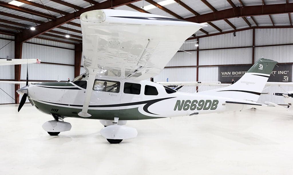 Side view of a white and green Cessna Stationair TC, registration N669DB, parked in a hangar.