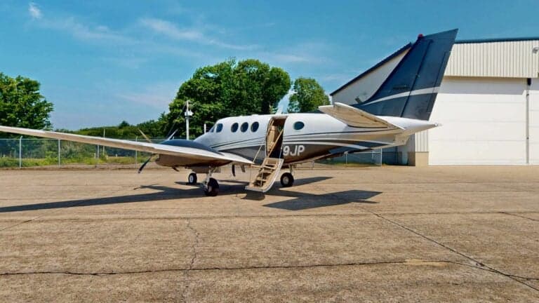 King Air aircraft parked on the tarmac with the airstair door open.