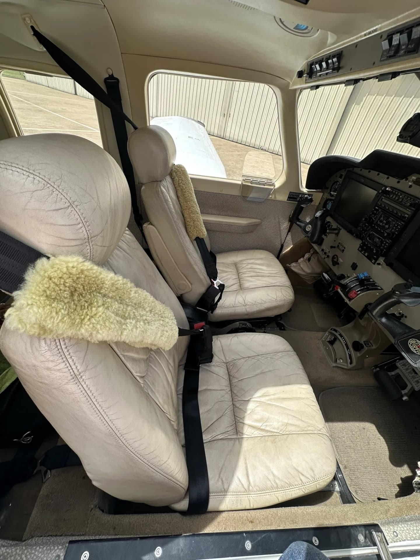 The light tan leather interior seats of the Piper Saratoga II TC aircraft, with sheepskin covers on the front seats.