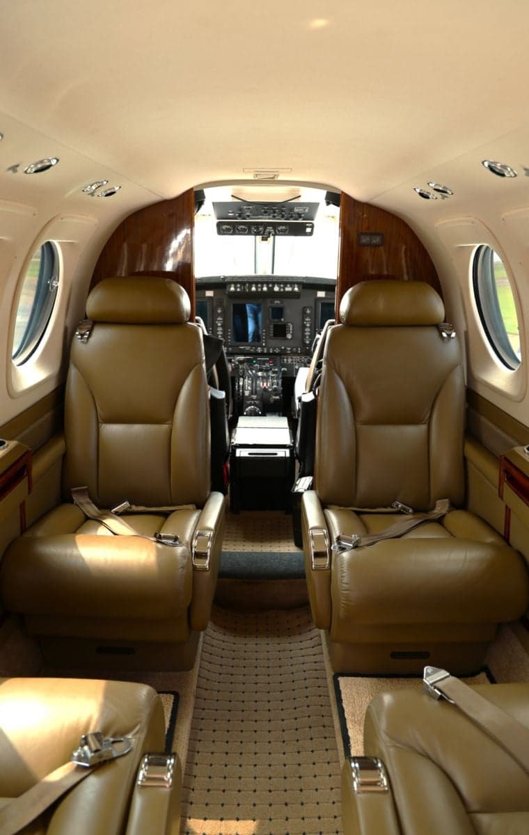 Interior view of an aircraft showing leather seats and the cockpit.