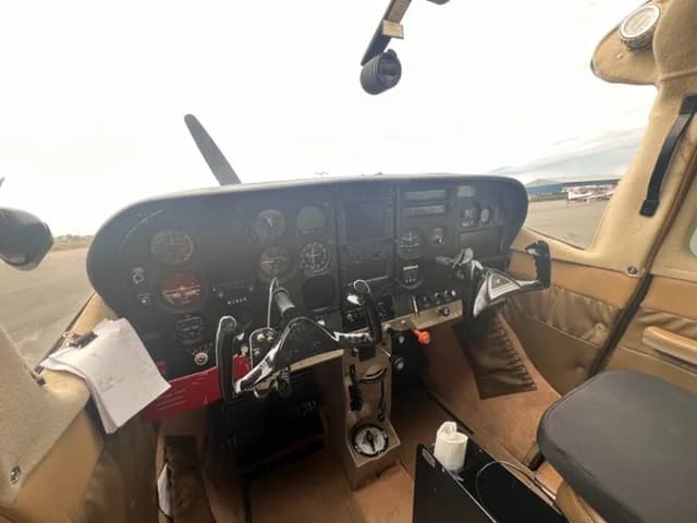 A wide view of the Cessna 182 cockpit, featuring the instrument panel, yokes, and tan interior.