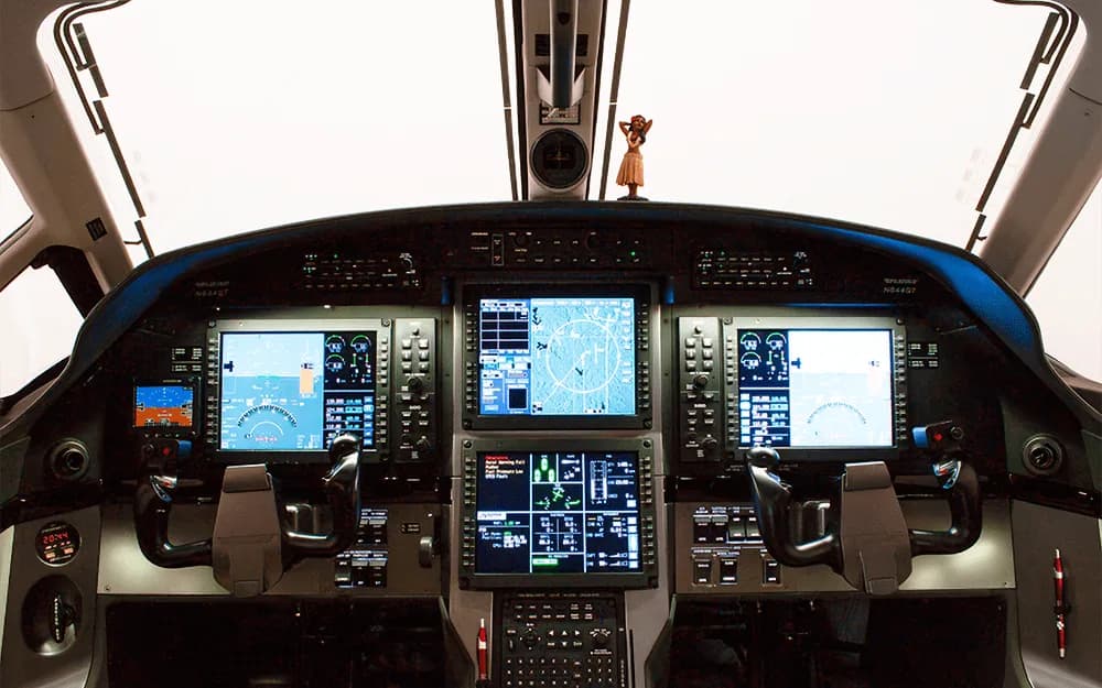 The cockpit of a Pilatus PC-12 NGX features multiple large digital displays and control yokes.