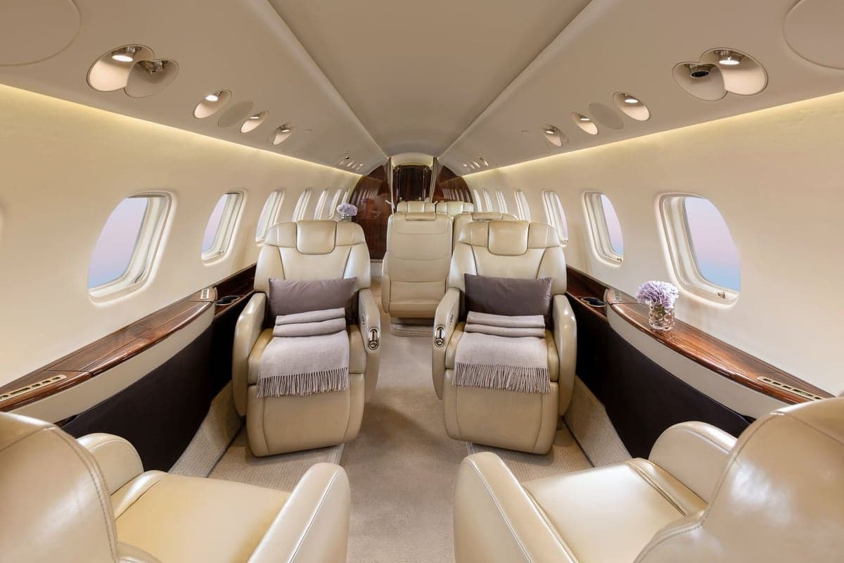 View of the Embraer Legacy 500 cabin with leather seats and wood trim.
