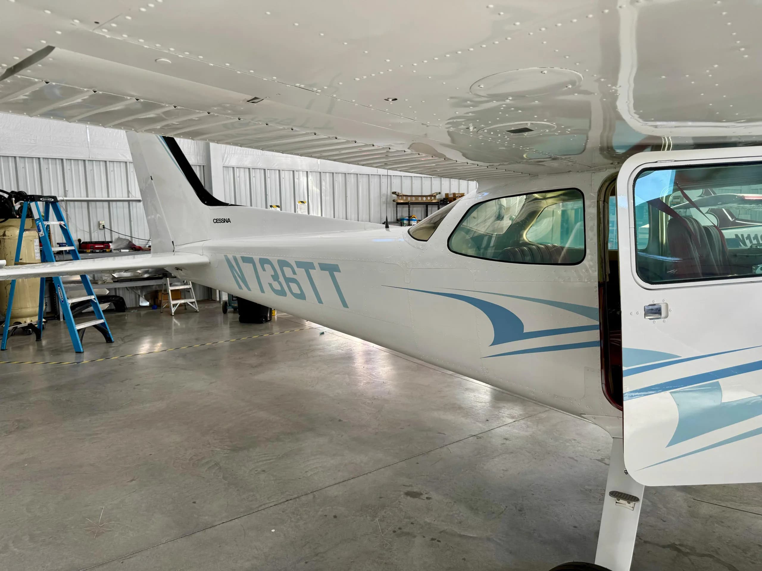 A close-up side view of the fuselage and tail of a white Cessna 172 Hawk XP, showing registration N736TT.