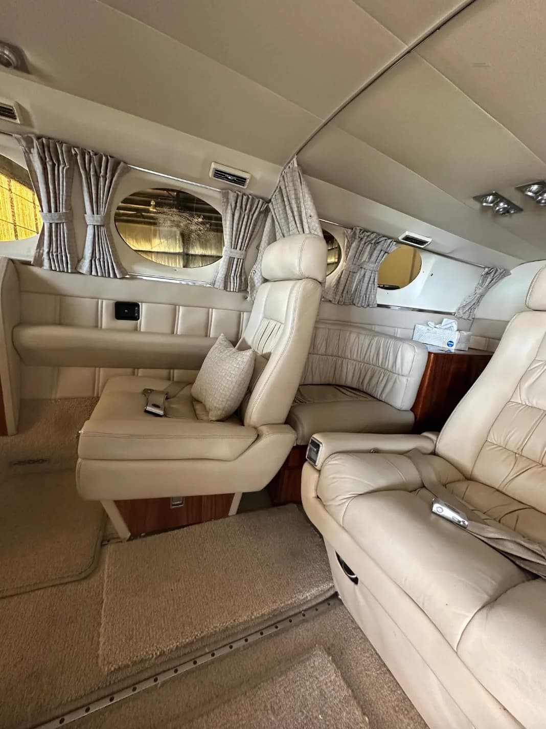 A close-up view of the beige leather seats and window curtains in the aircraft's cabin.