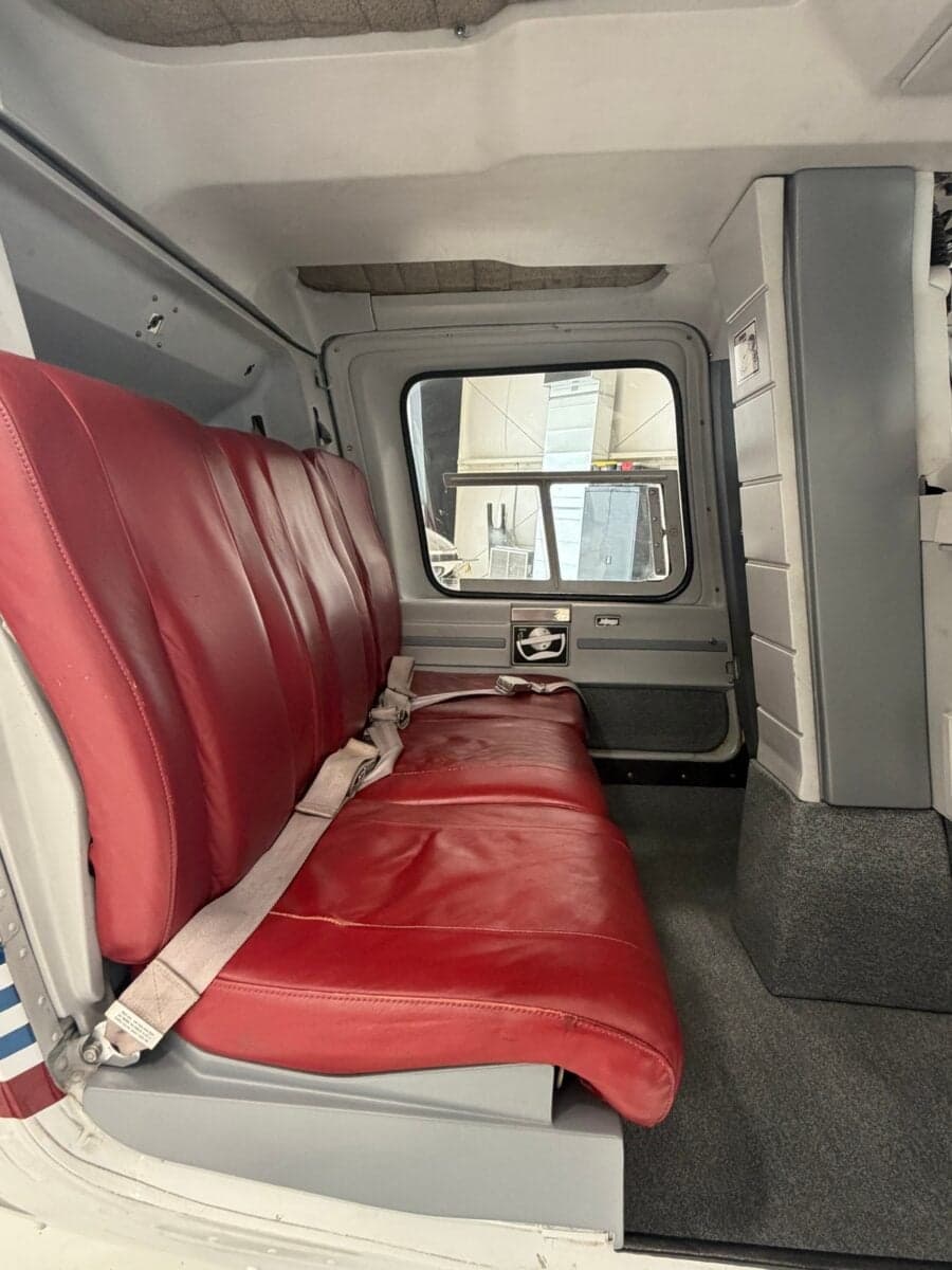 The rear bench seat of a Bell 206B JetRanger helicopter, upholstered in red leather.