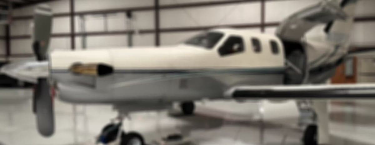 Blurred side view of a turboprop aircraft in a hangar.