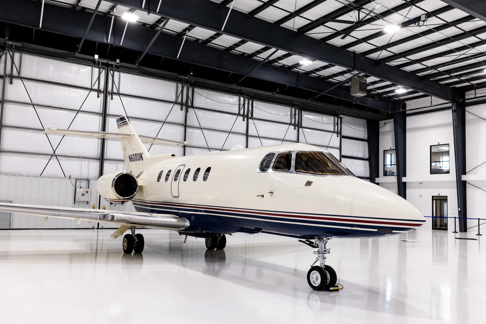 The N800UK business jet is parked inside a brightly lit modern hangar.
