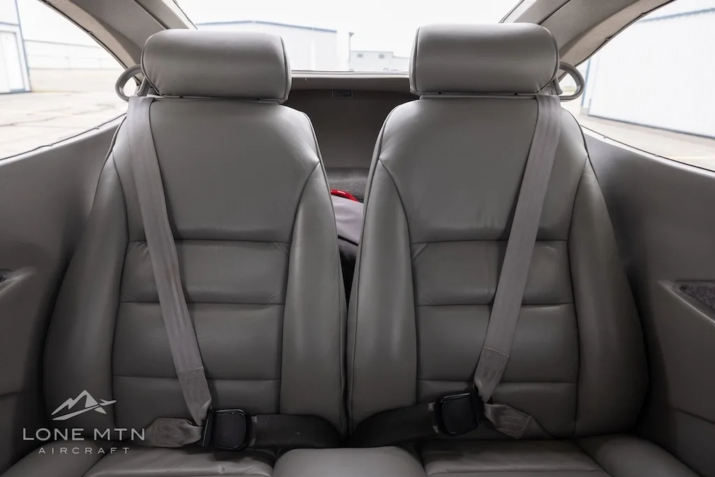 A straight-on view of the grey leather rear passenger seats in an aircraft cabin.