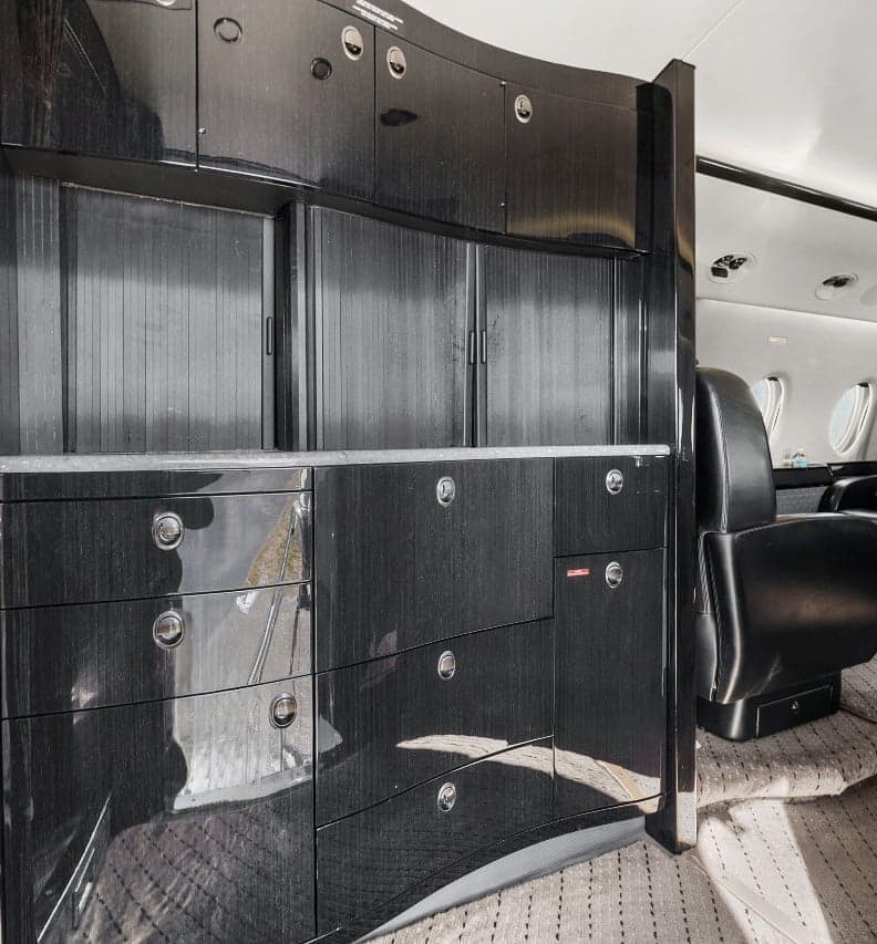A view of the interior of the aircraft, showing the cabinets and a seat.