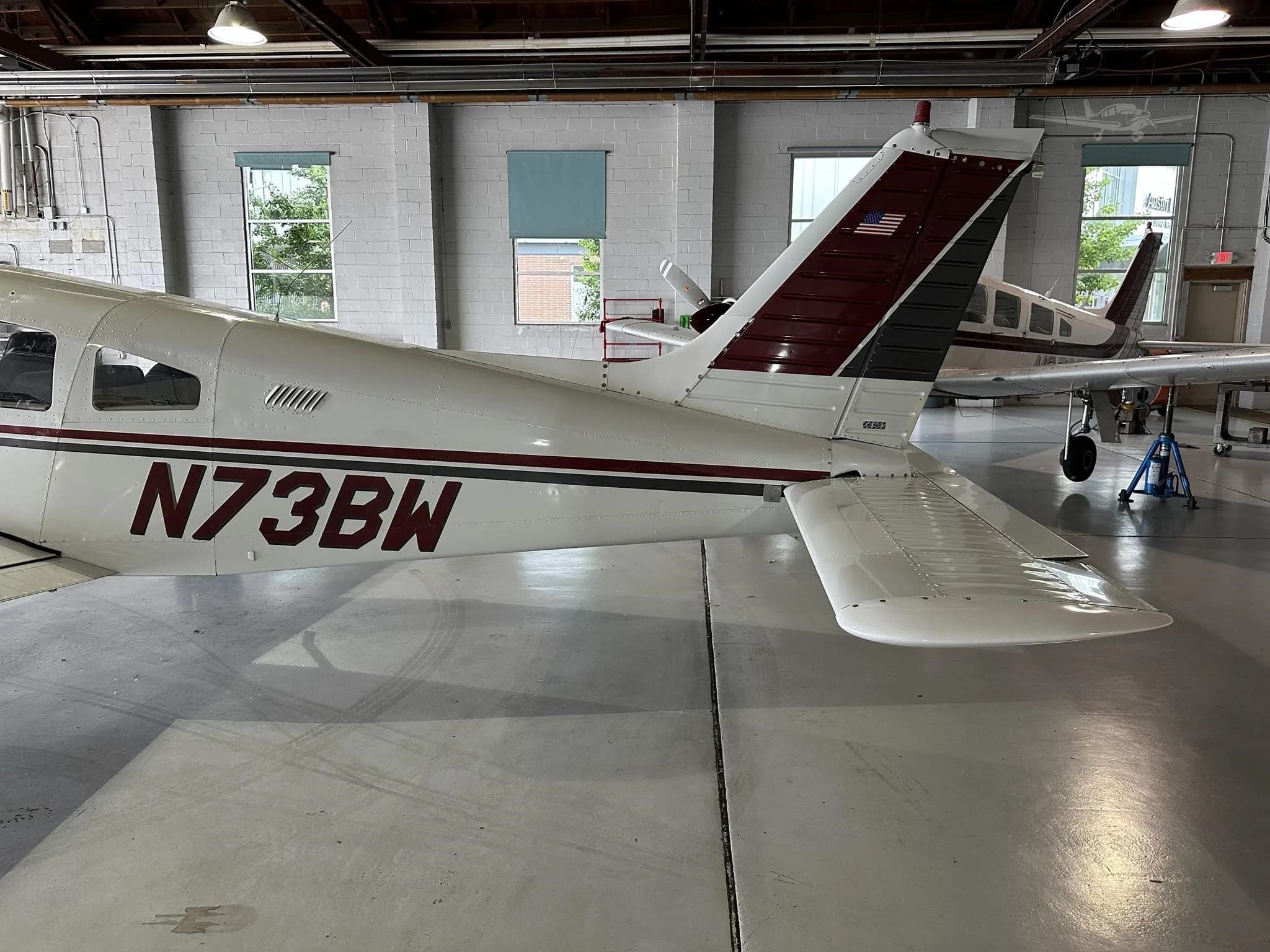 A close-up view of the tail section of the N73BW aircraft, showing the maroon and black stripe on the tail.