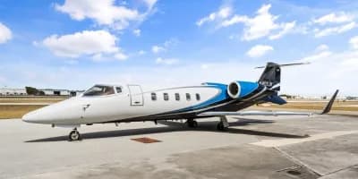 A Learjet 45XR with a white, blue, and black paint scheme is parked on the tarmac.