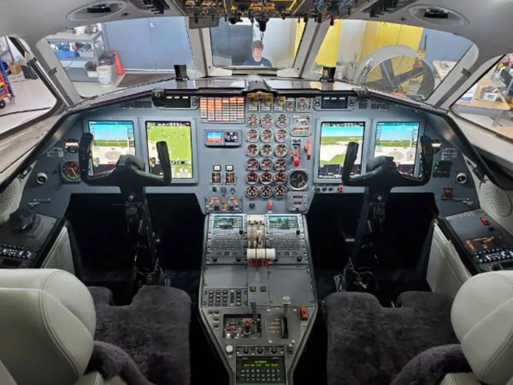 The modern cockpit of a Dassault Falcon 900EX, featuring multiple digital displays and control yokes.