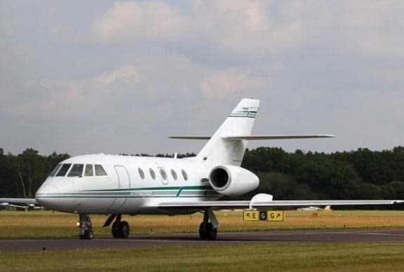 A white and green Falcon jet on the tarmac.