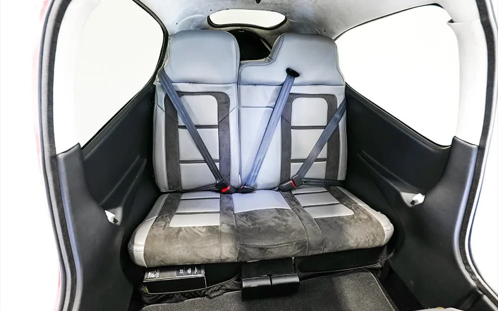 The gray and black leather rear bench seat of a Cirrus SR22 aircraft, with two seatbelts visible.