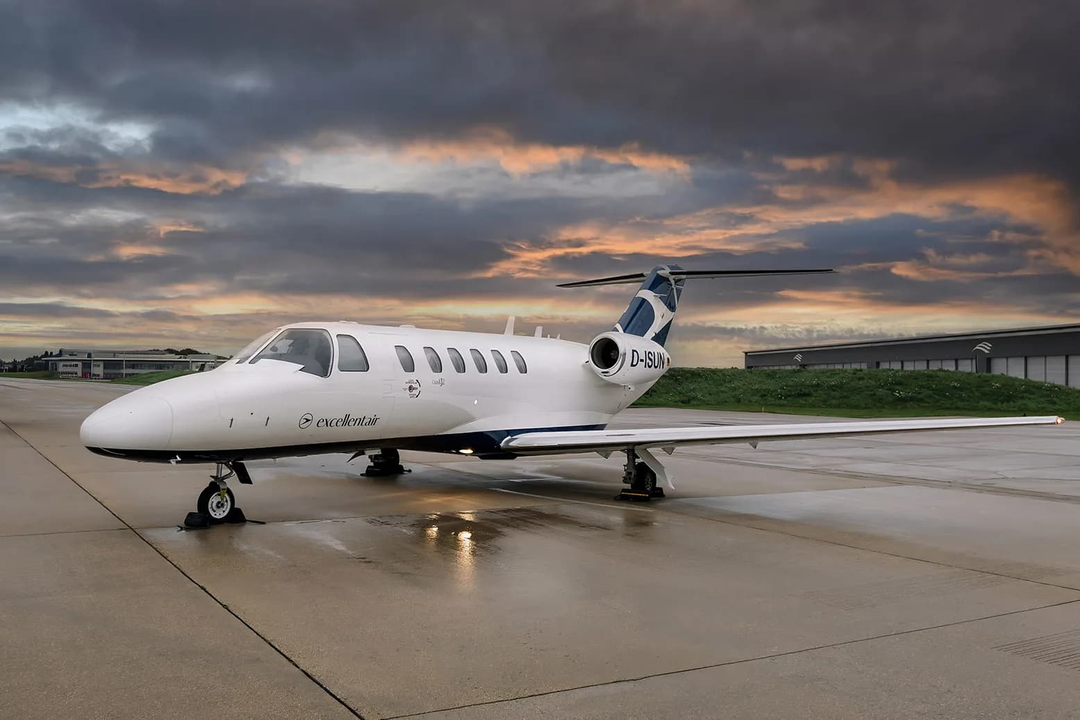 A Cessna Citation CJ2 aircraft with registration D-ISUN parked on the tarmac at dusk.